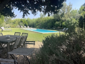 A pool area with a rectangular pool, surrounded by a well-maintained lawn and several lounge chairs.