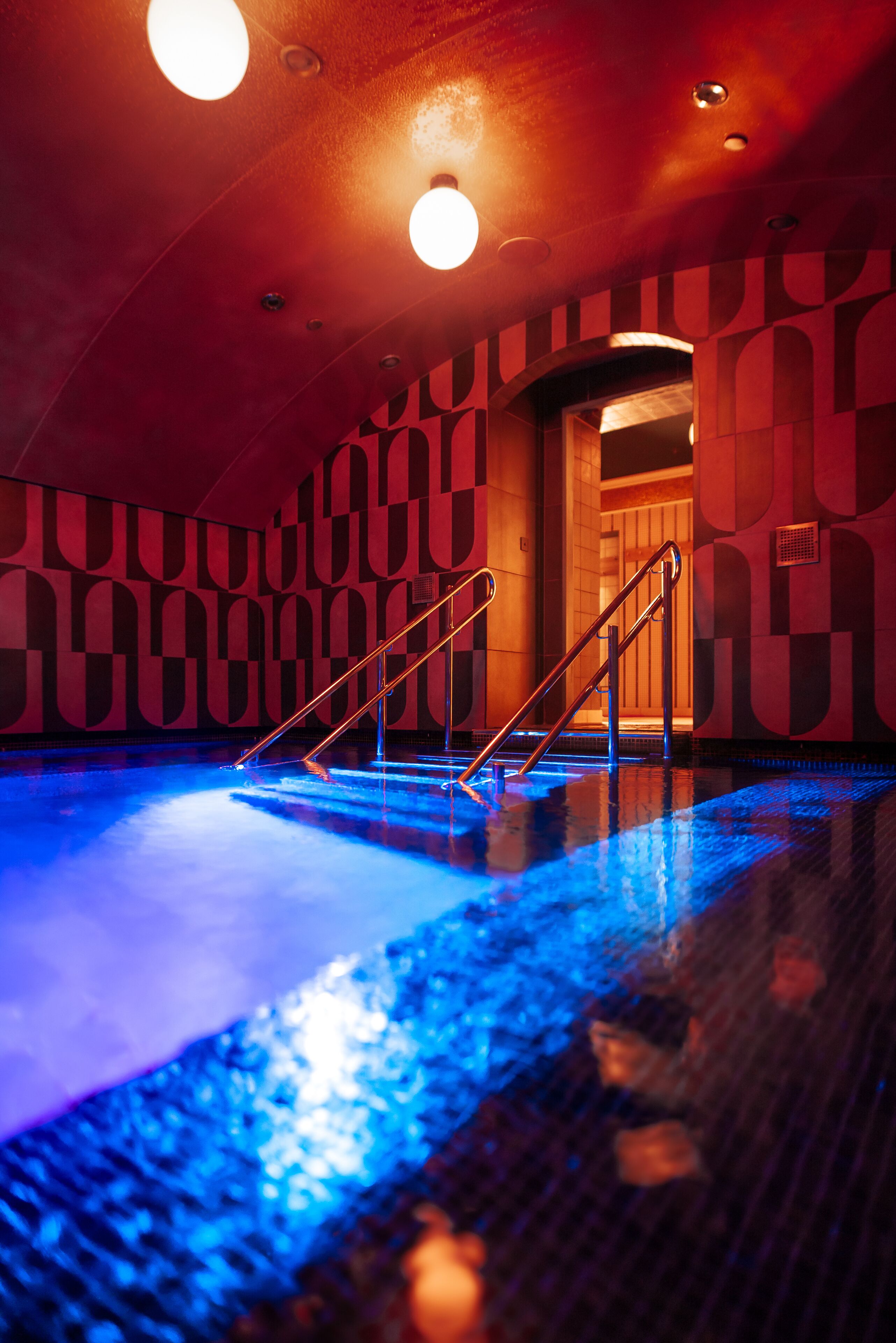 A swimming pool with a geometric wall pattern and a staircase leading to an upper level.
