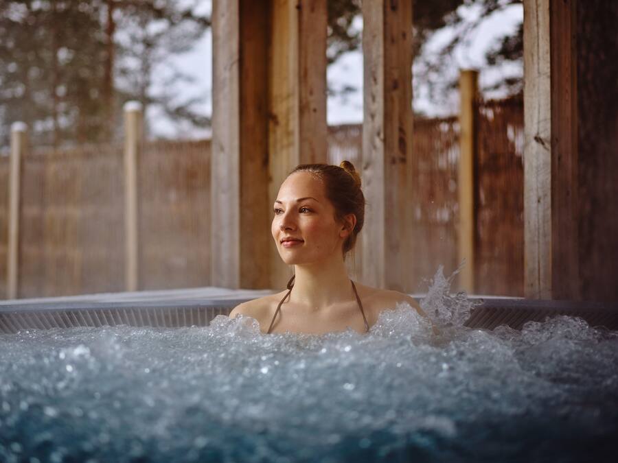 En person i ett bubbelbad, med ett trästaket i bakgrunden.