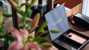 Un teléfono inteligente en una caja con un mensaje, un jarrón con flores y una mesa de madera.