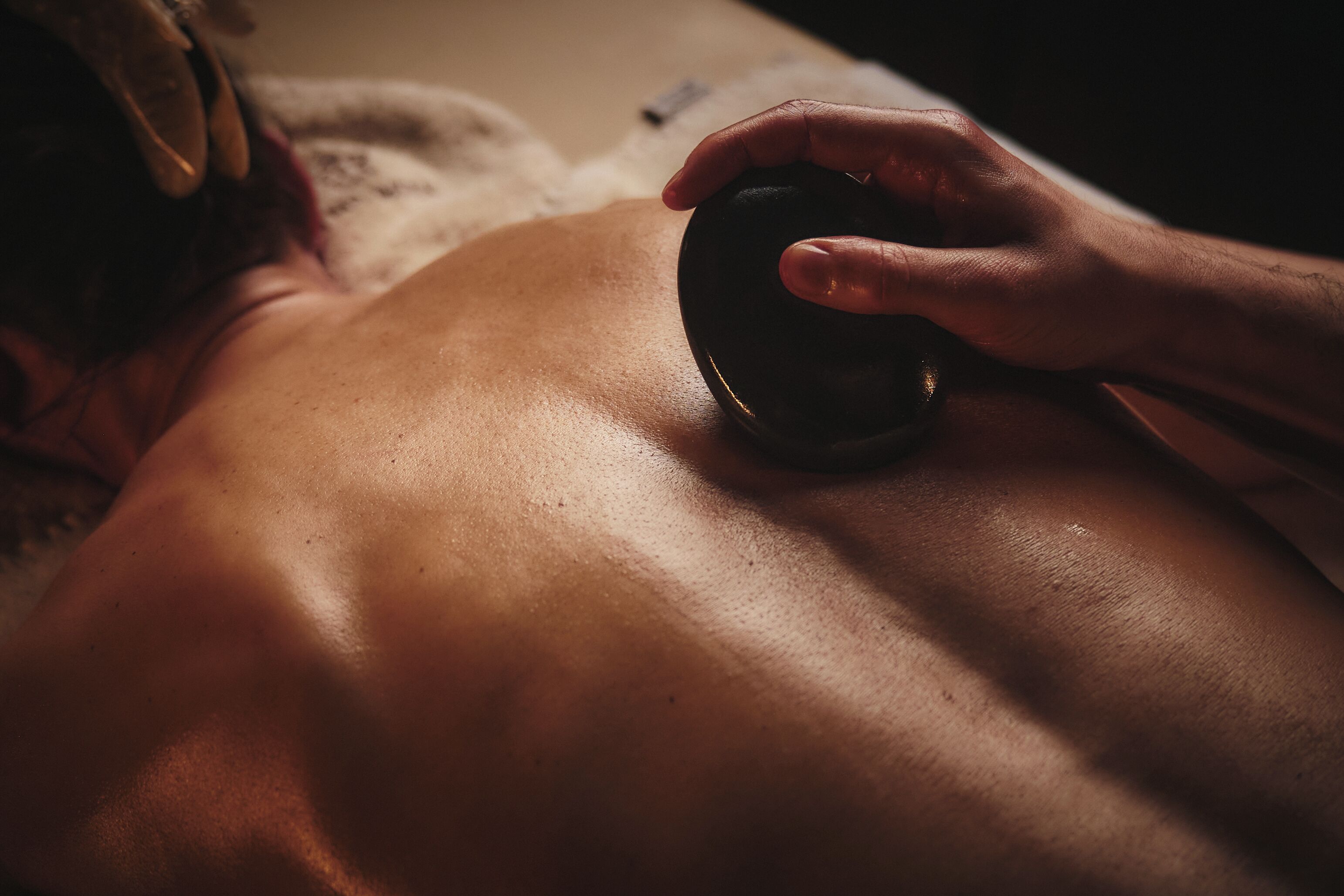 En närbild på en hand som håller en massageboll mot en persons rygg.