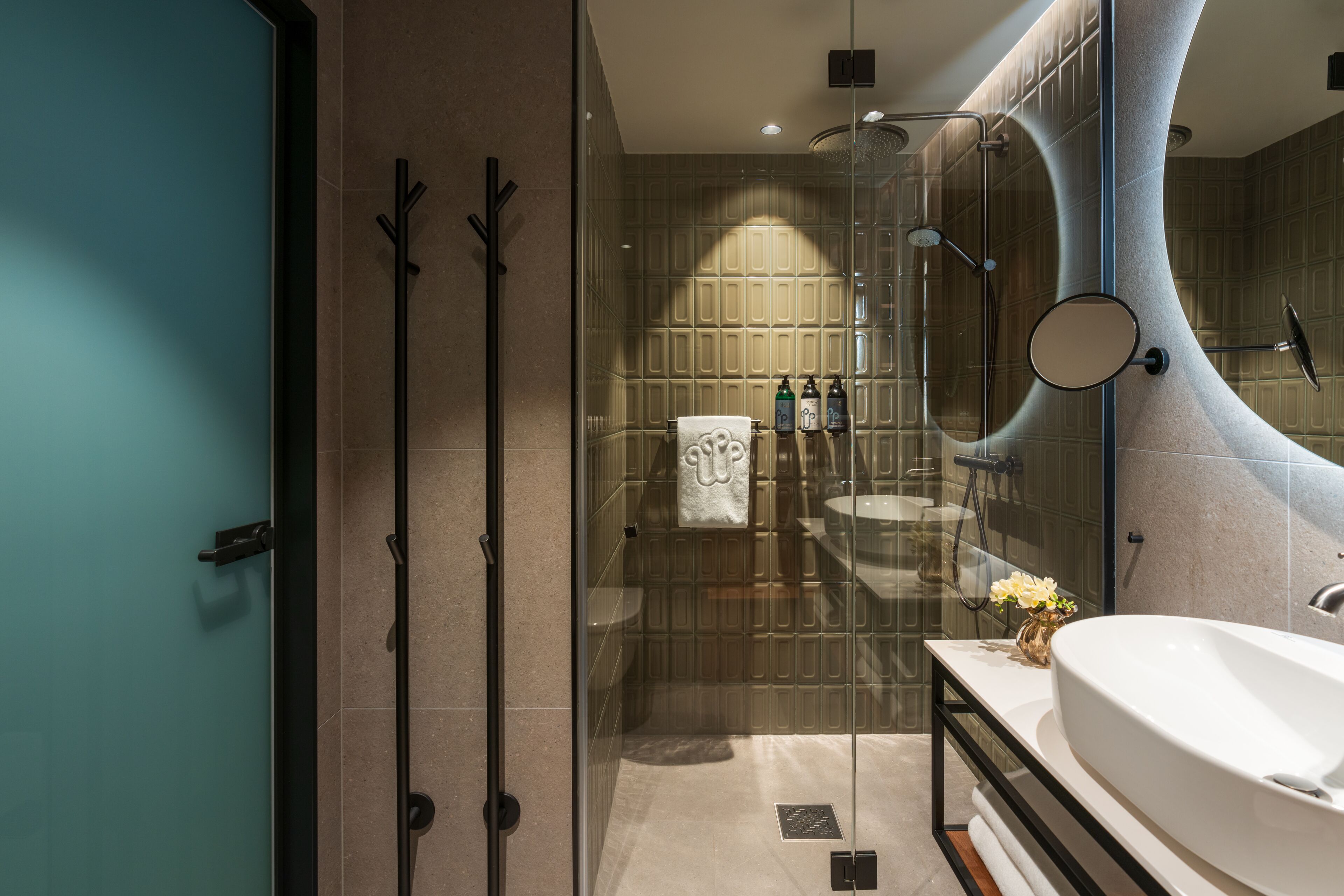 Une salle de bain moderne avec une douche à l’italienne en verre, un grand lavabo et un miroir.