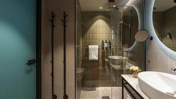 Une salle de bain moderne avec une douche à l’italienne en verre, un grand lavabo et un miroir.
