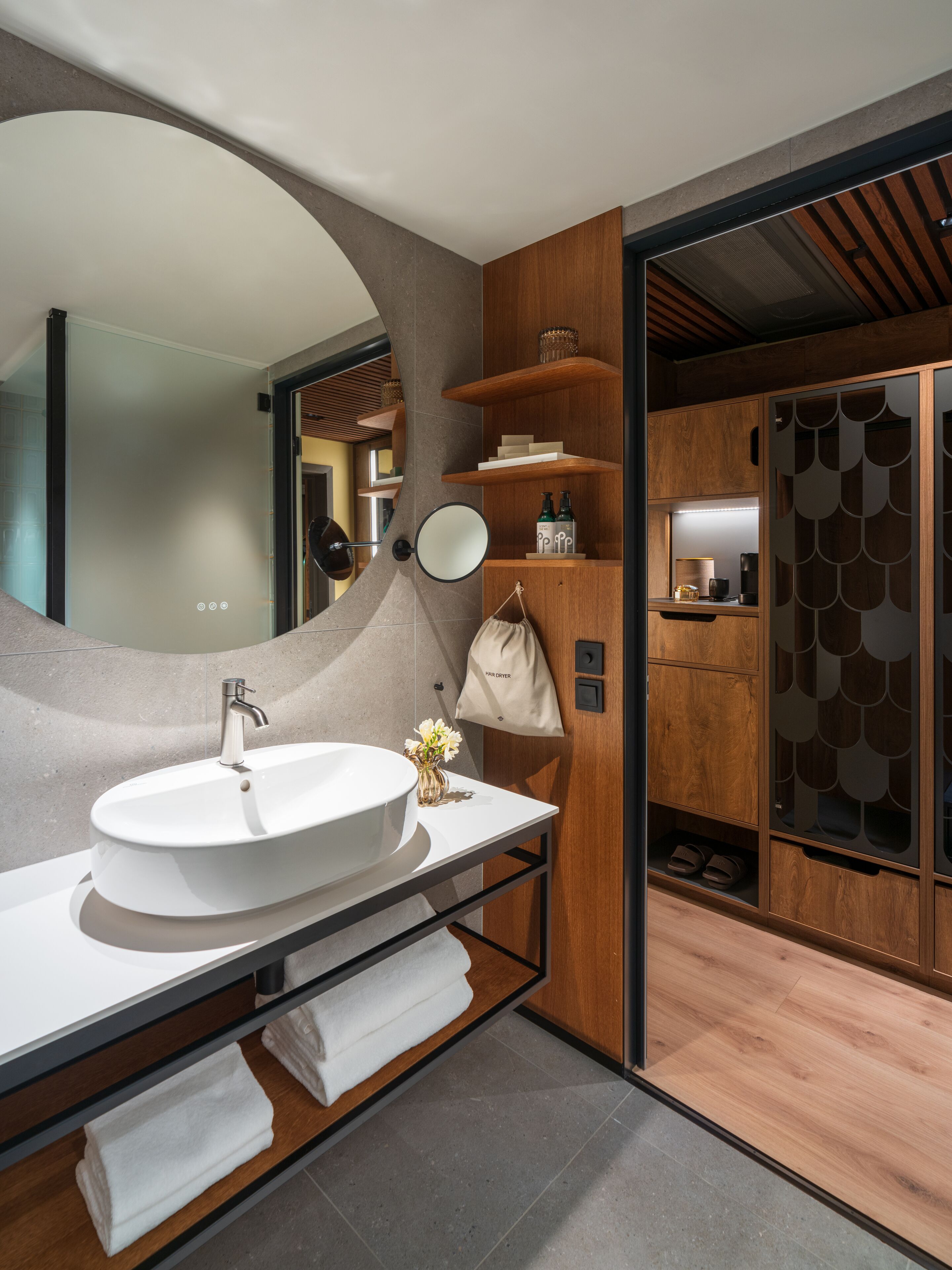 A modern bathroom with a large oval sink, a mirror, and wooden shelves.