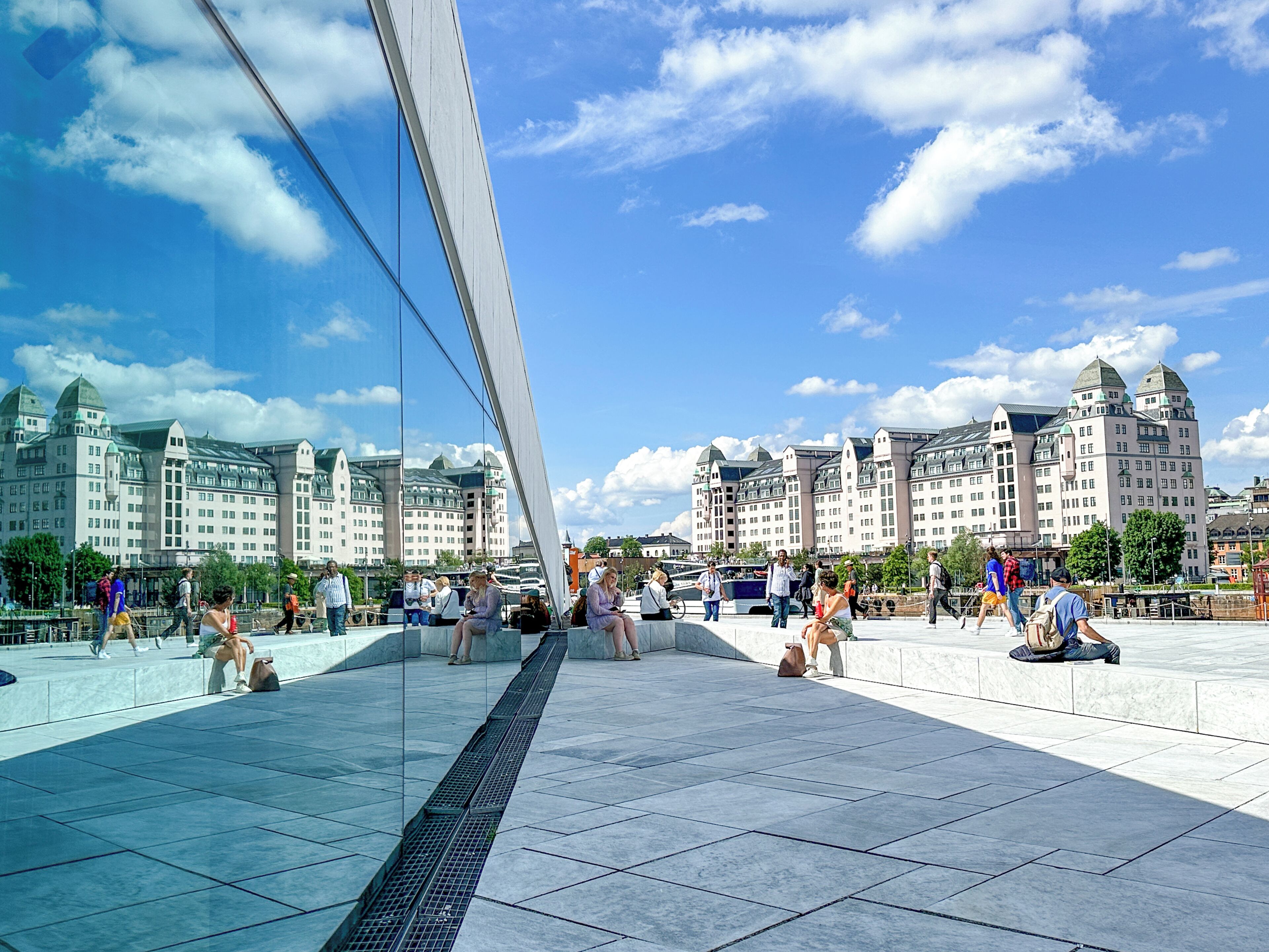 A modern glass bridge with a clear view of historic buildings in the background.