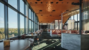 A modern restaurant with large windows, wooden ceiling, and a view of the forest. - The Well Spa & Hotel (Nordre Follo)