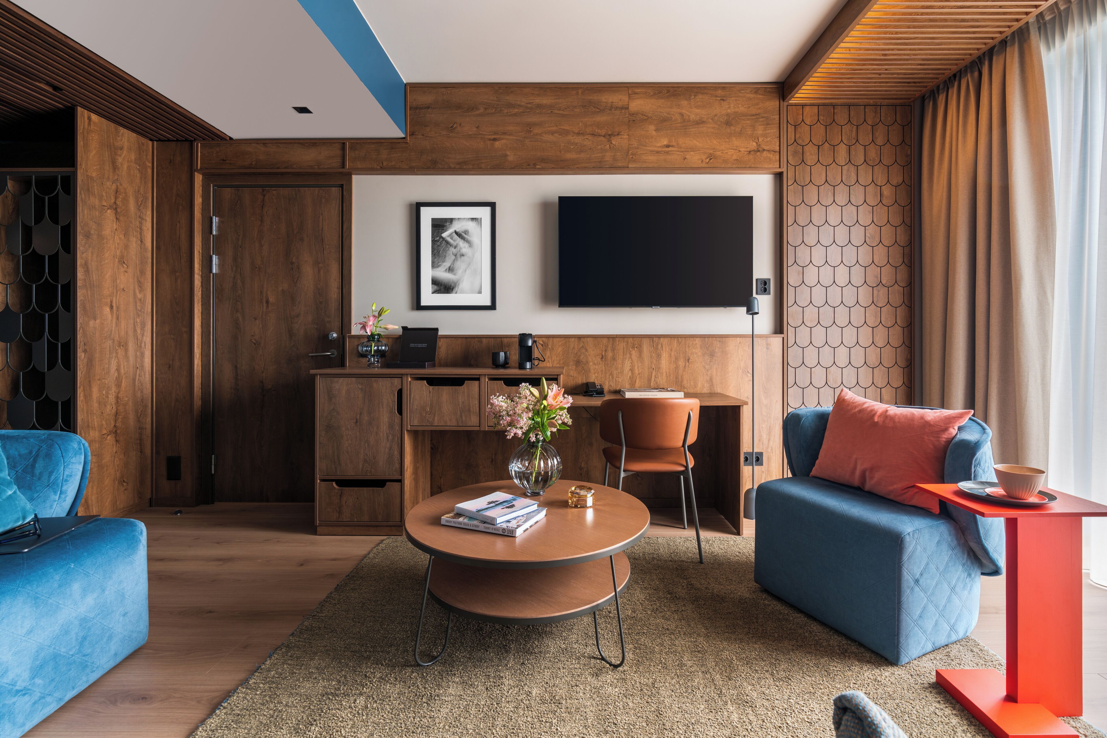 Un salon moderne avec un canapé bleu, une table basse ronde et un téléviseur fixé au mur.