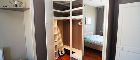 Une chambre à coucher avec un lit, une armoire et un miroir.