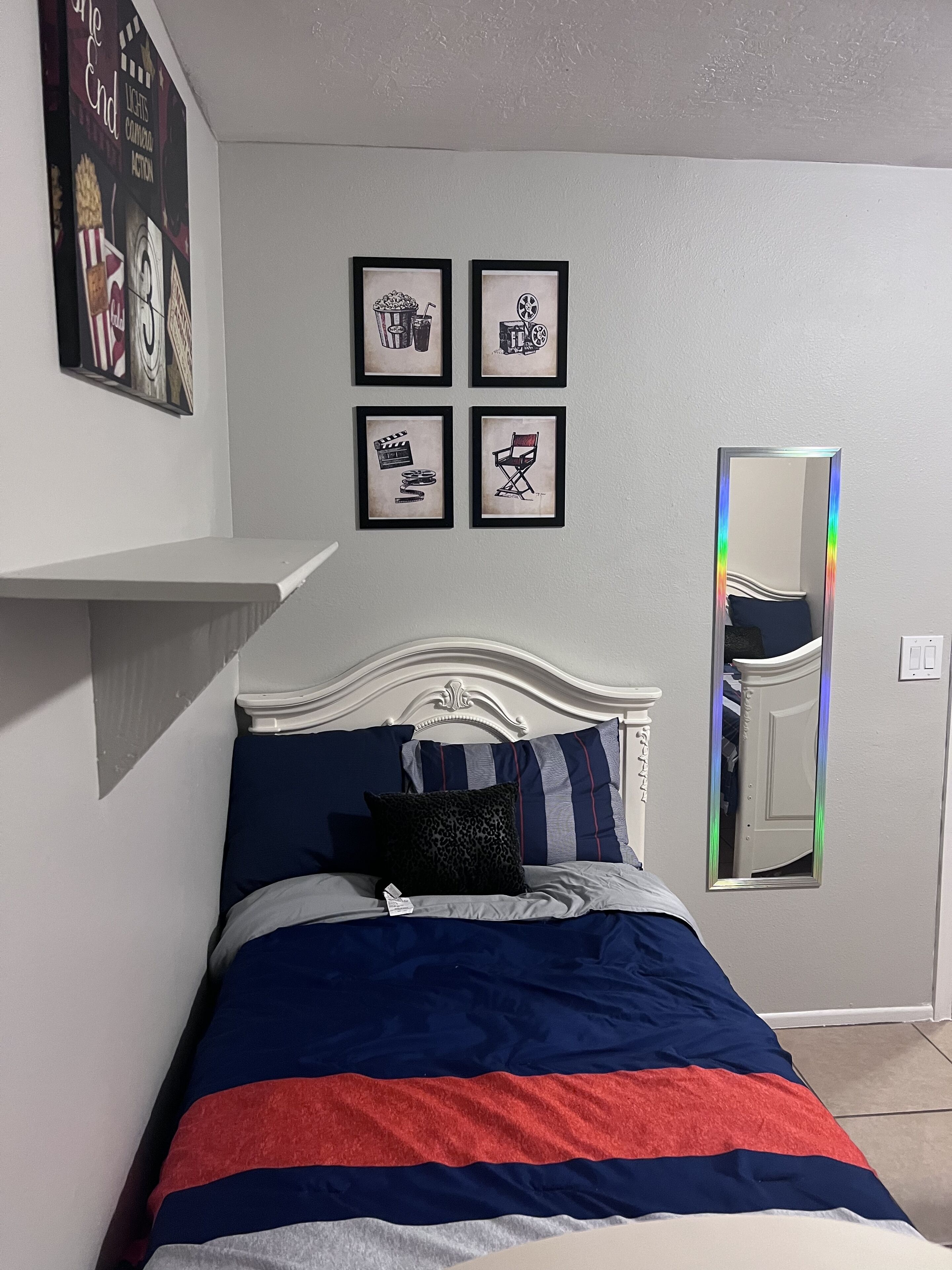 A bedroom with a bed, a nightstand, a mirror, and four framed pictures on the wall.