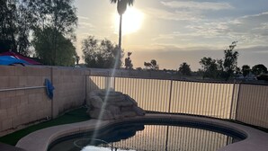 A swimming pool with a wooden deck, surrounded by a fence and a palm tree. - Pool home in Phoenix Retreat close to everything! (Phoenix)