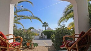A view from a covered patio with wicker chairs, a clear blue sky, and palm trees. - Shangrila by Interhome (Calpe/Calp)