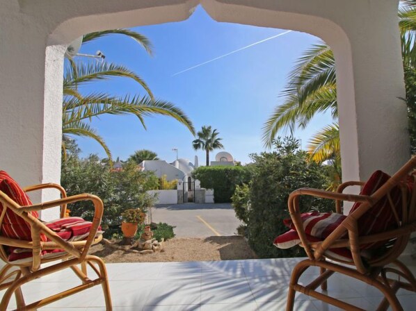 Relax in a serene patio setting with two comfortable chairs and a stunning view of a historic building.