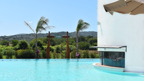 Una piscina con un cartel que dice "Hyéle" y una vista de un paisaje verde exuberante al fondo.