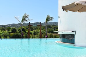 Une piscine avec un panneau indiquant « Hyéle » et, en arrière-plan, une vue sur un paysage verdoyant et luxuriant.