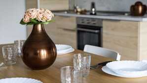 Et spisebord med en vase blomster, klare glas og hvide tallerkener.
