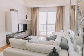 A modern living room with a white sofa, a flat-screen TV, a marble coffee table, and a balcony with curtains. - MY WAY HOTEL & EVENTS (Patras)