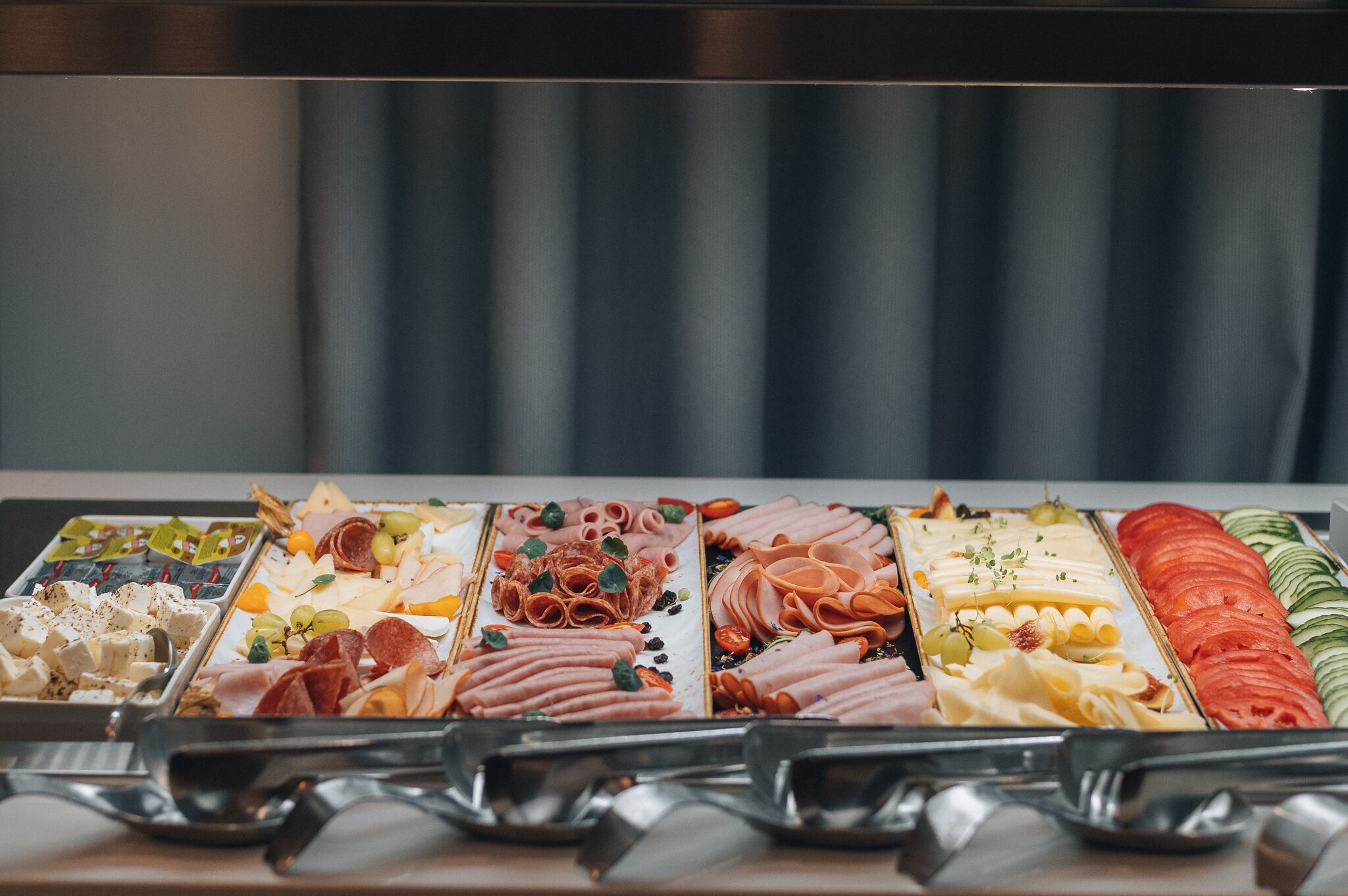 Ein reichhaltiges Buffet mit verschiedenen Speisen, darunter Fleisch, Käse und Gemüse.