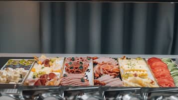 A buffet with various food items including meats, cheeses, and vegetables.