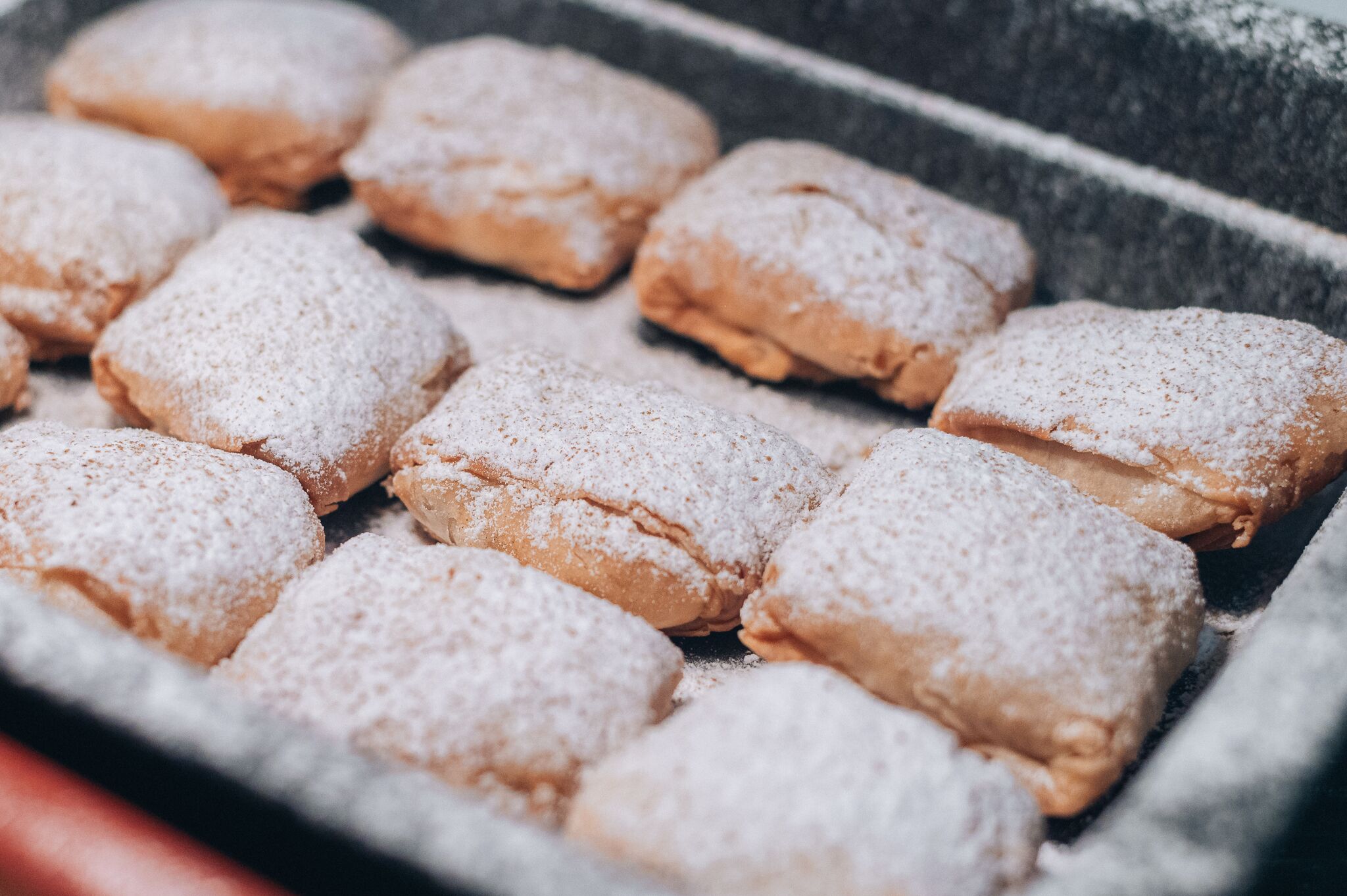A tray of pastries dusted with powdered sugar.