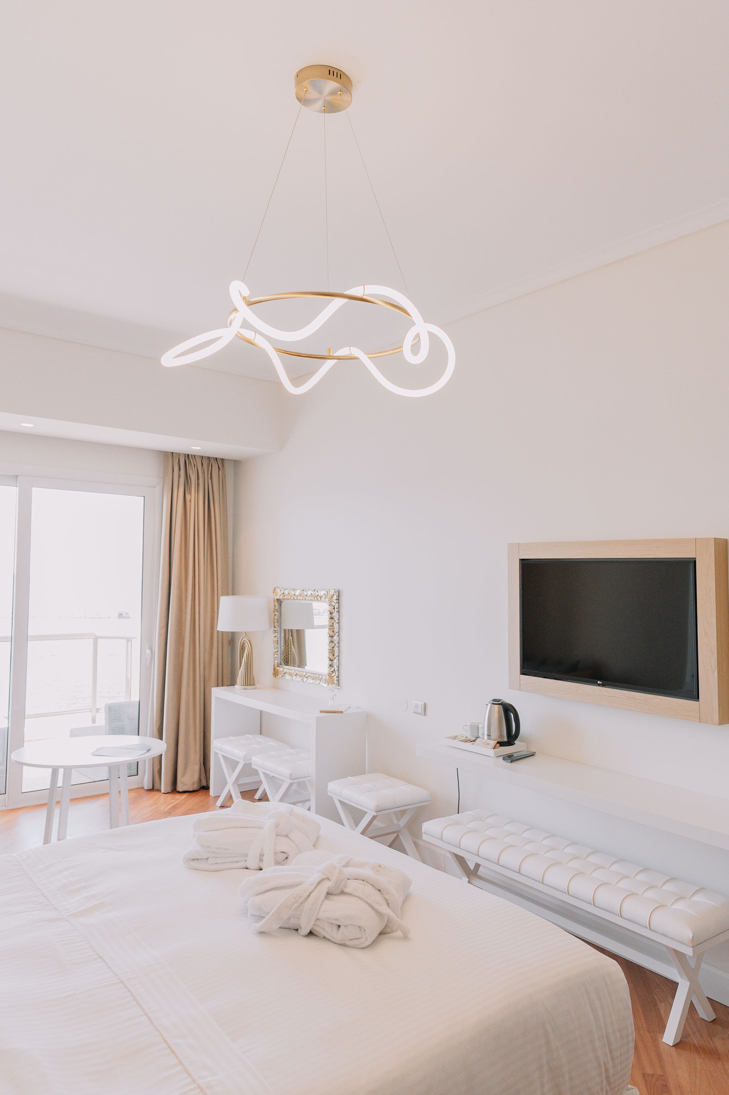 Una habitación de hotel moderna con una cama grande, un escritorio, un banco y un televisor.