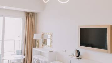 Quarto de hotel moderno com uma cama grande, uma escrivaninha, um banco e uma televisão.