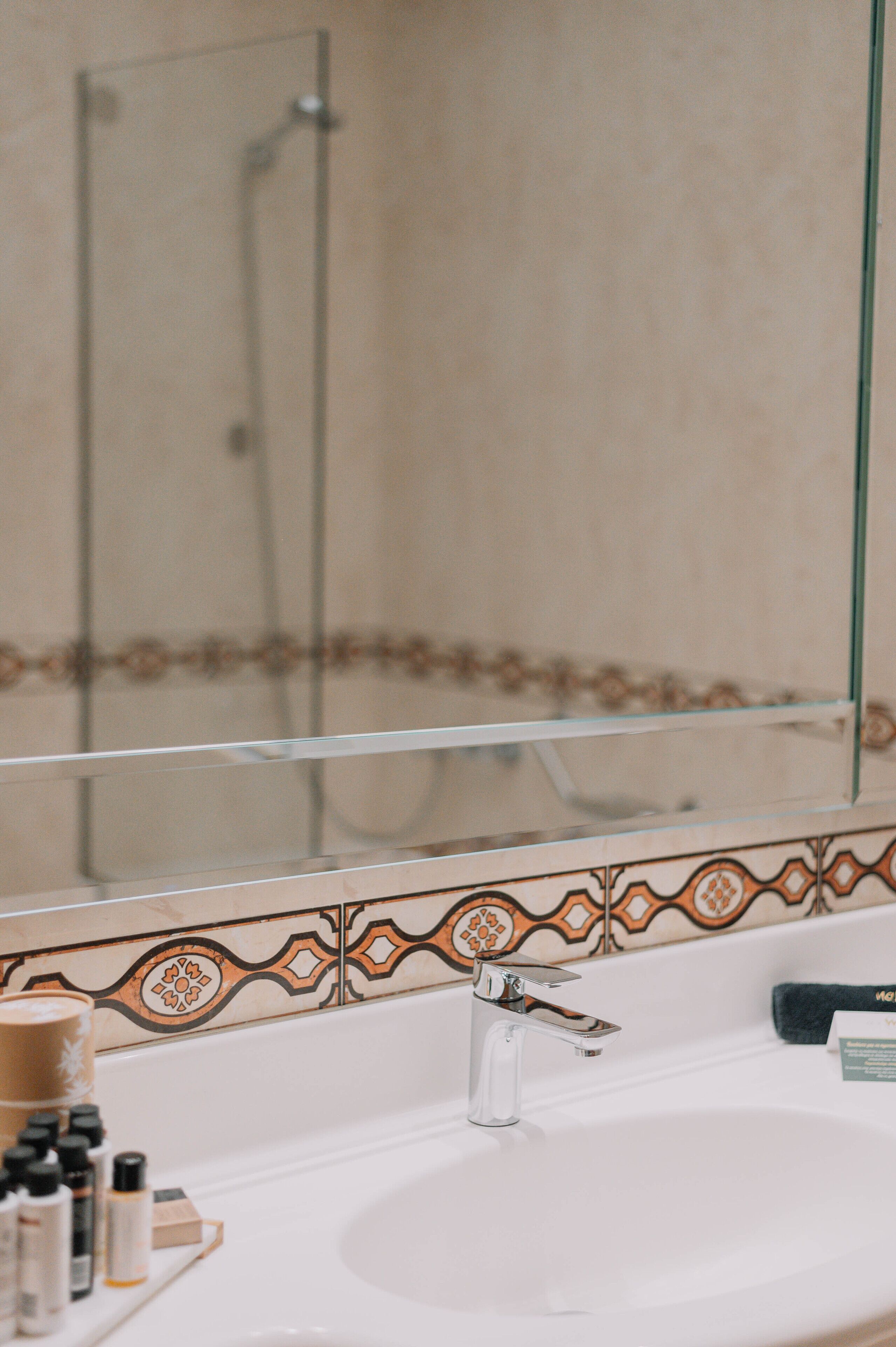 A bathroom with a sink, mirror, and shower.