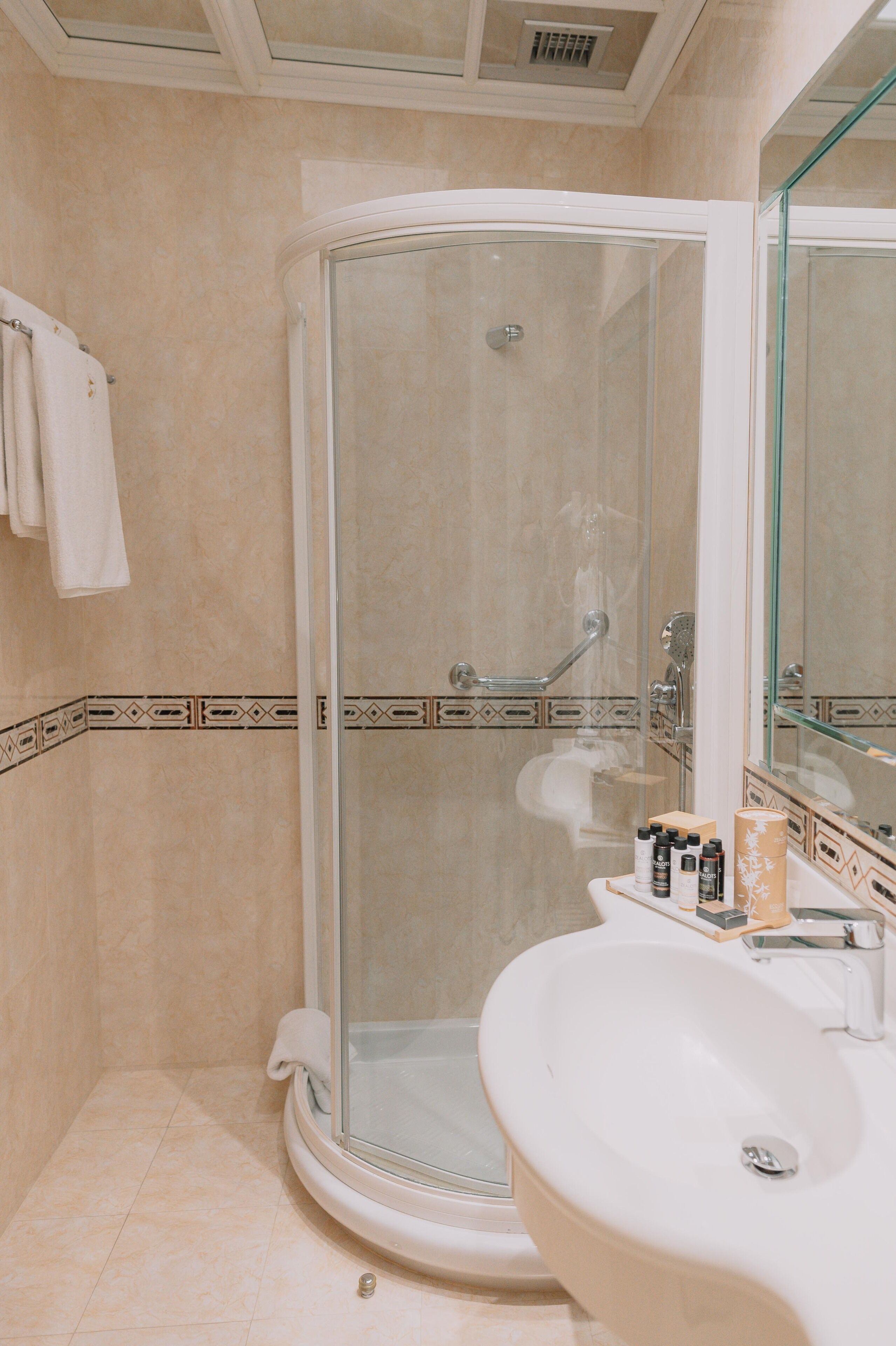 A modern bathroom with a glass-enclosed shower, a white sink, and a mirror.