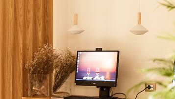 A wooden desk with a computer monitor, keyboard, and two white chairs.