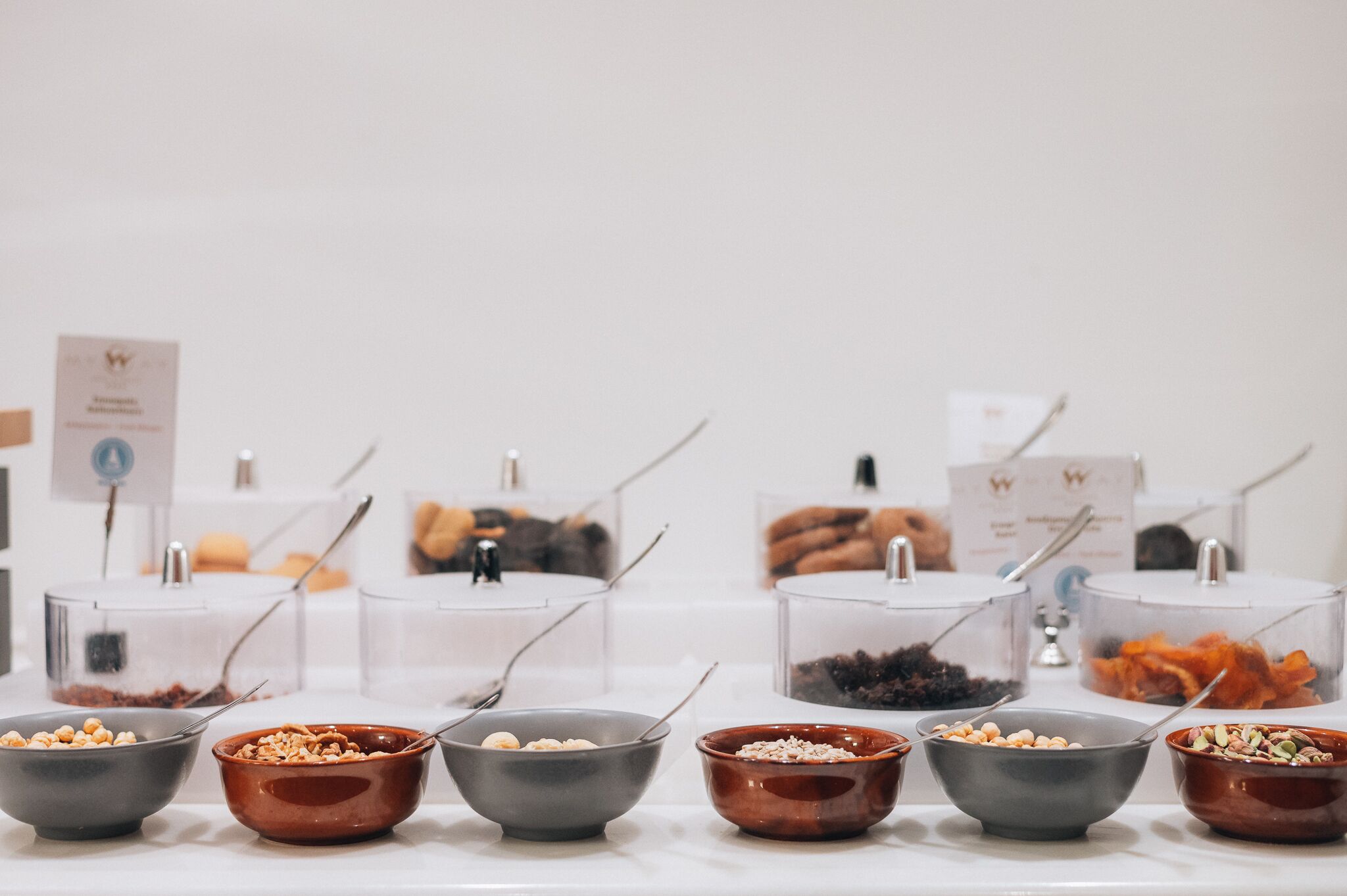 Un buffet disposé avec des récipients en verre transparent contenant différents aliments, ainsi que des bols remplis de noix et de fruits secs.