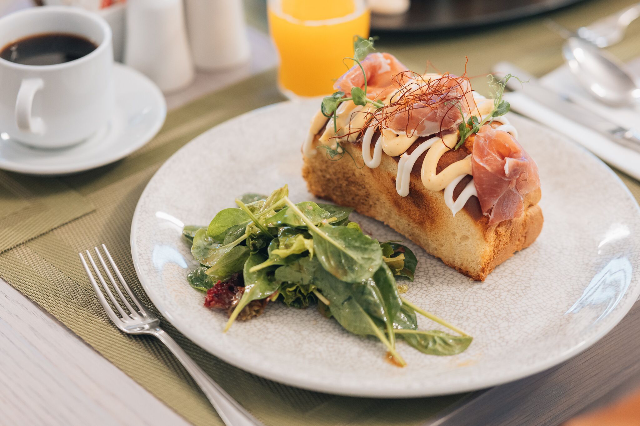 A plate with a sandwich, a cup of coffee, and a glass of orange juice on a table.