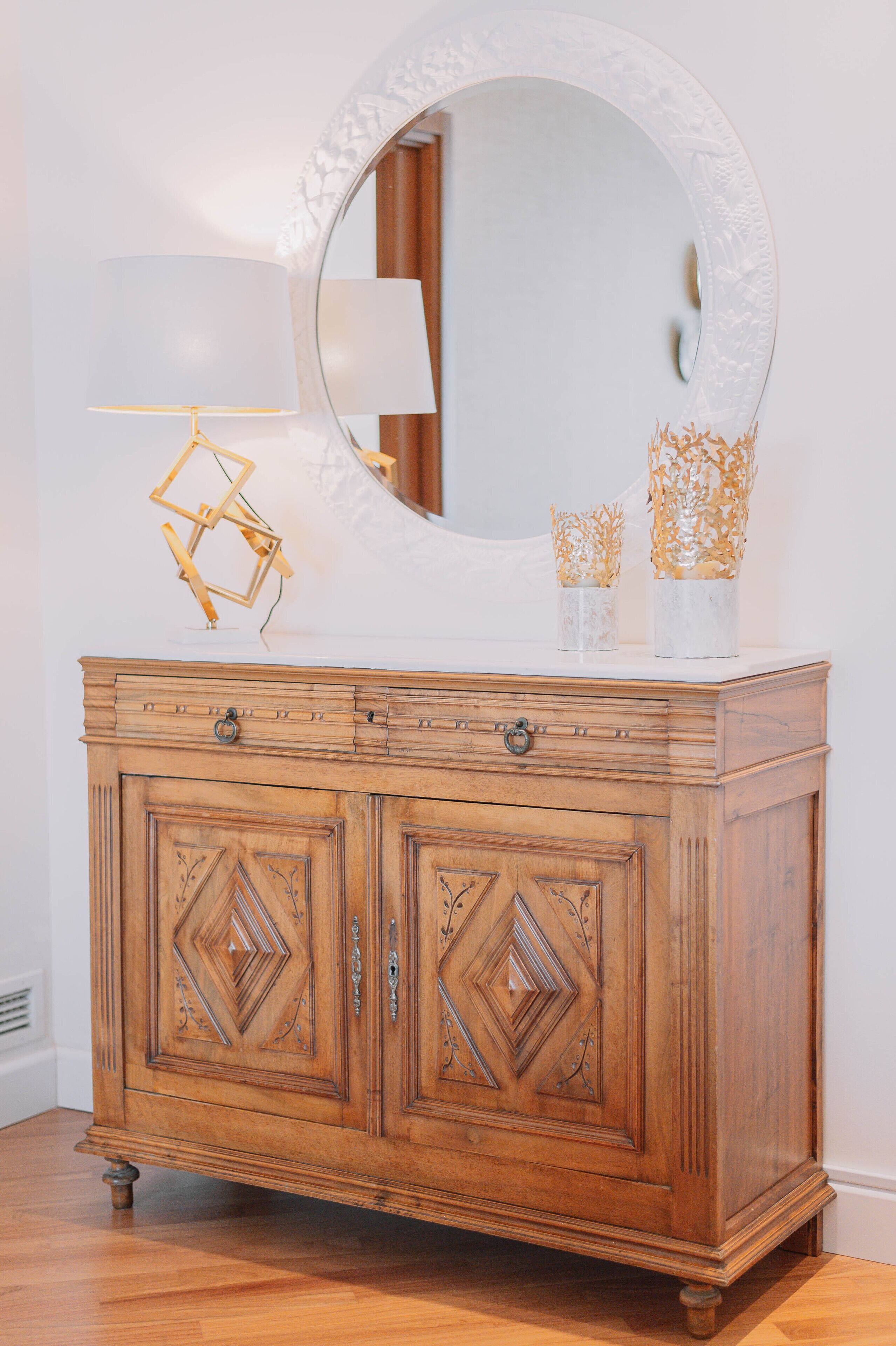 A wooden cabinet with a large mirror and decorative items on top.