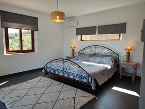 A bedroom with a bed, two bedside tables, a hanging light, a window with a view, and a wall-mounted air conditioner. - Villa Las Adelfas with beautiful view ,HEATED POOL, 6 Pers, WIFI,BBQ,terraces (Benamargosa)
