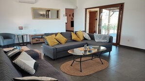 A modern living room with a grey sofa, yellow cushions, a glass coffee table, and a large mirror on the wall. - Villa Las Adelfas with beautiful view ,HEATED POOL, 6 Pers, WIFI,BBQ,terraces (Benamargosa)