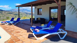 A terrace with blue lounge chairs, a covered seating area, and a view of mountains. - Villa Las Adelfas with beautiful view ,HEATED POOL, 6 Pers, WIFI,BBQ,terraces (Benamargosa)