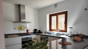 A modern kitchen with a central island, a stove, a sink, and a window with wooden frames. - Villa Las Adelfas with beautiful view ,HEATED POOL, 6 Pers, WIFI,BBQ,terraces (Benamargosa)