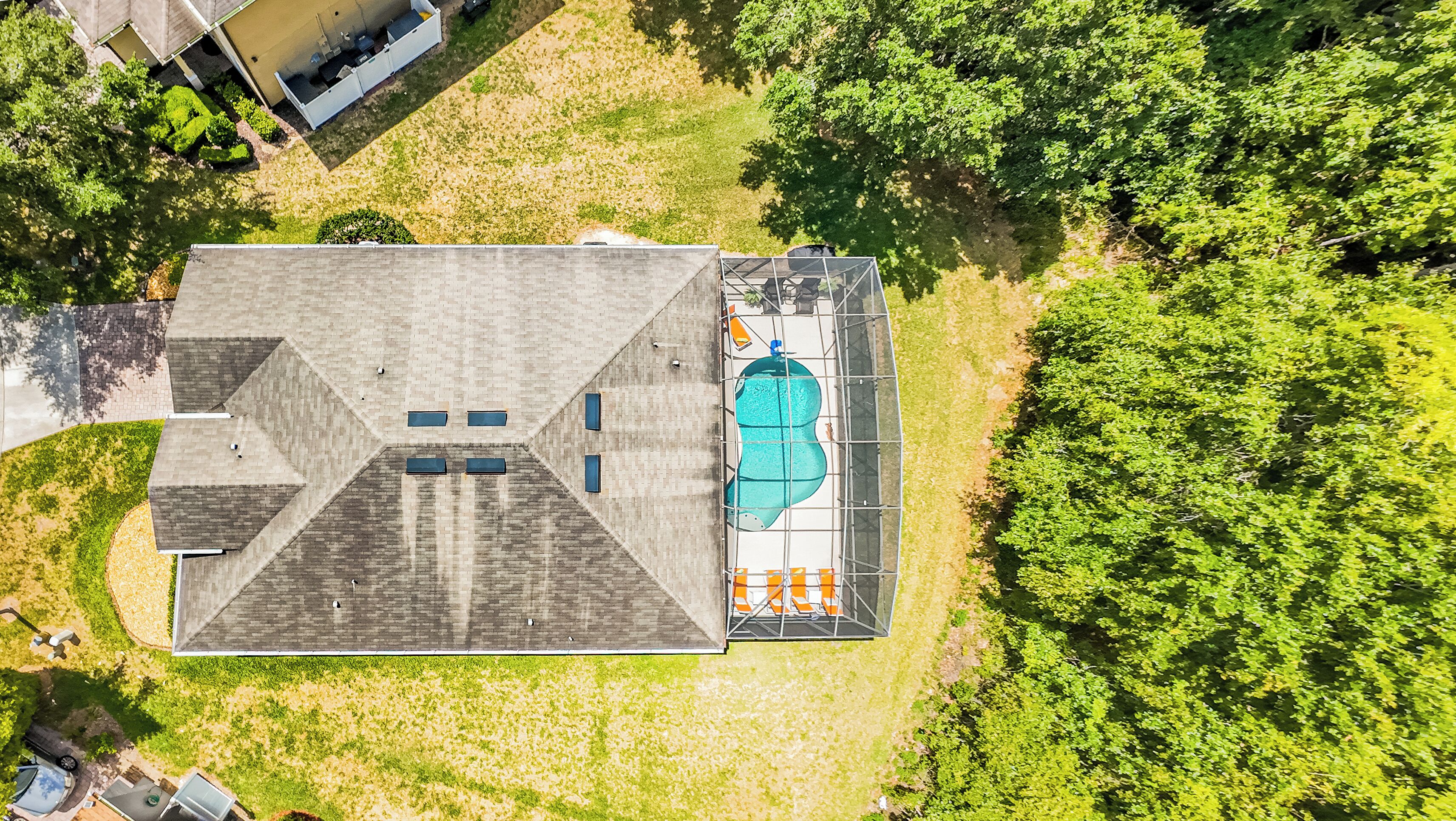 Vue aérienne d’un bâtiment doté d’une piscine, d’un patio couvert et d’un espace verdoyant environnant.