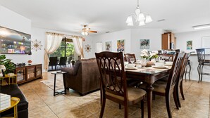 A dining area with a table set for four, surrounded by wooden chairs, a ceiling fan, and a chandelier. -  A-POP of Sunshine  (Davenport)