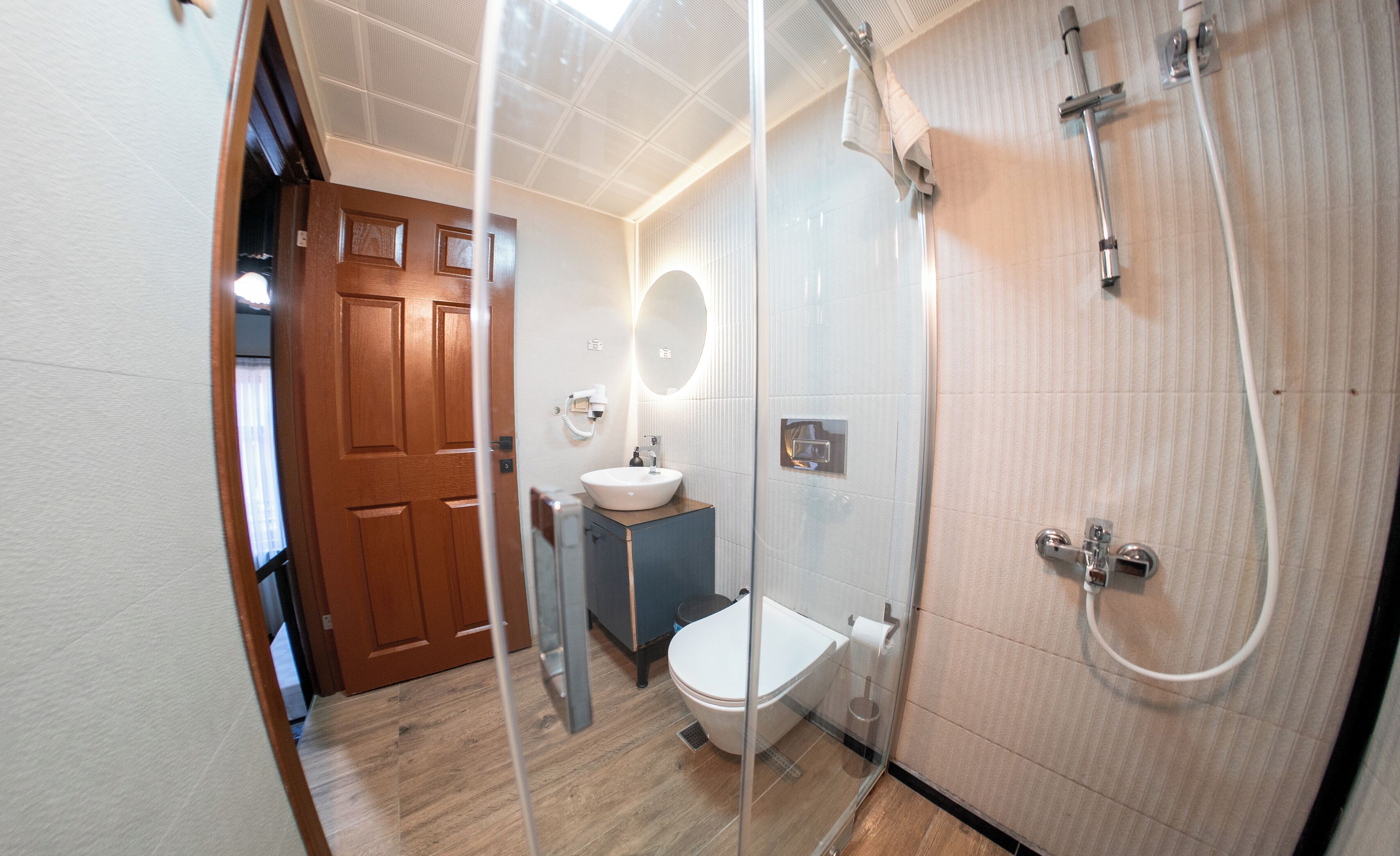 A modern bathroom with a glass shower enclosure, a toilet, and a sink.