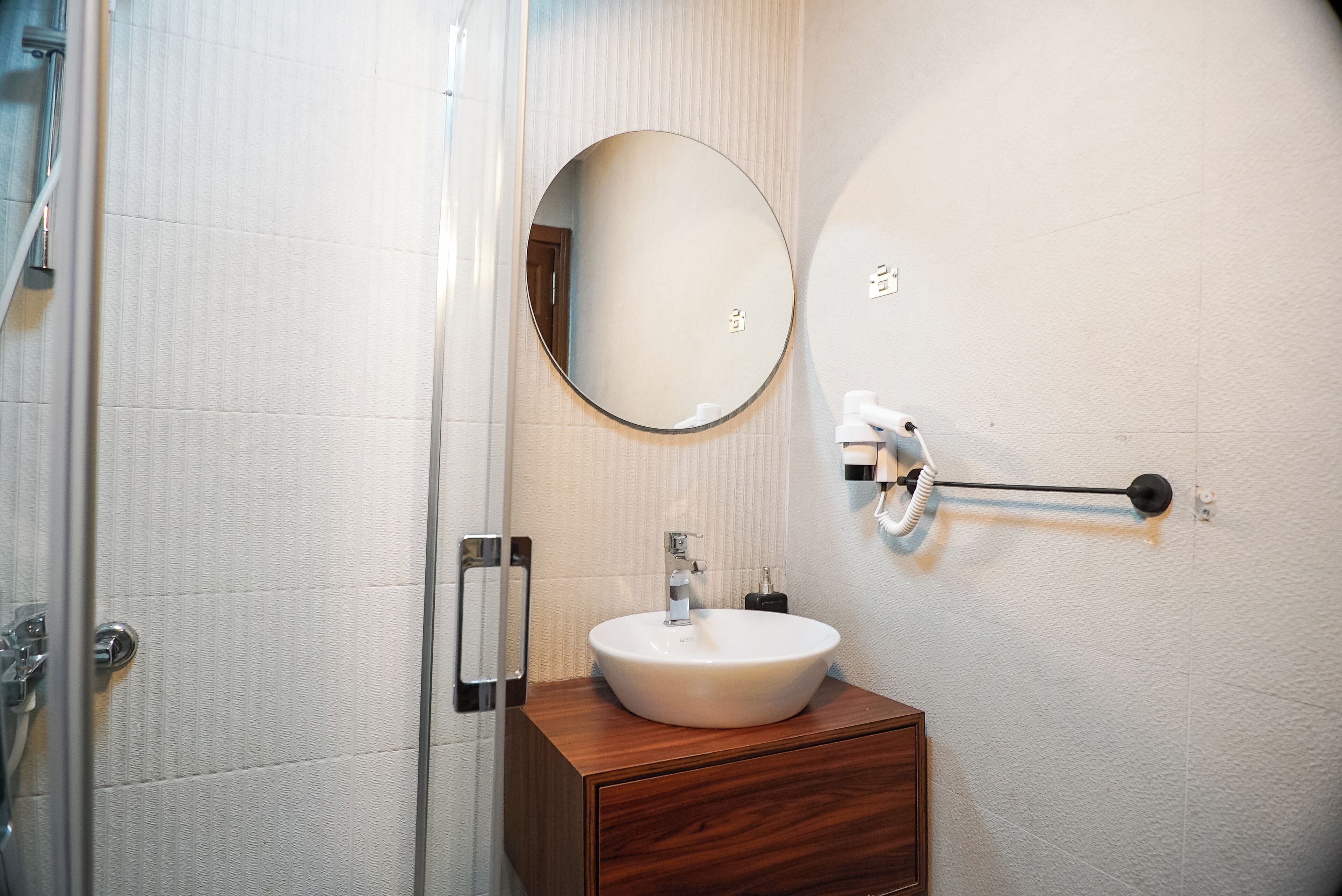 A bathroom with a white sink, a round mirror, and a towel rack.