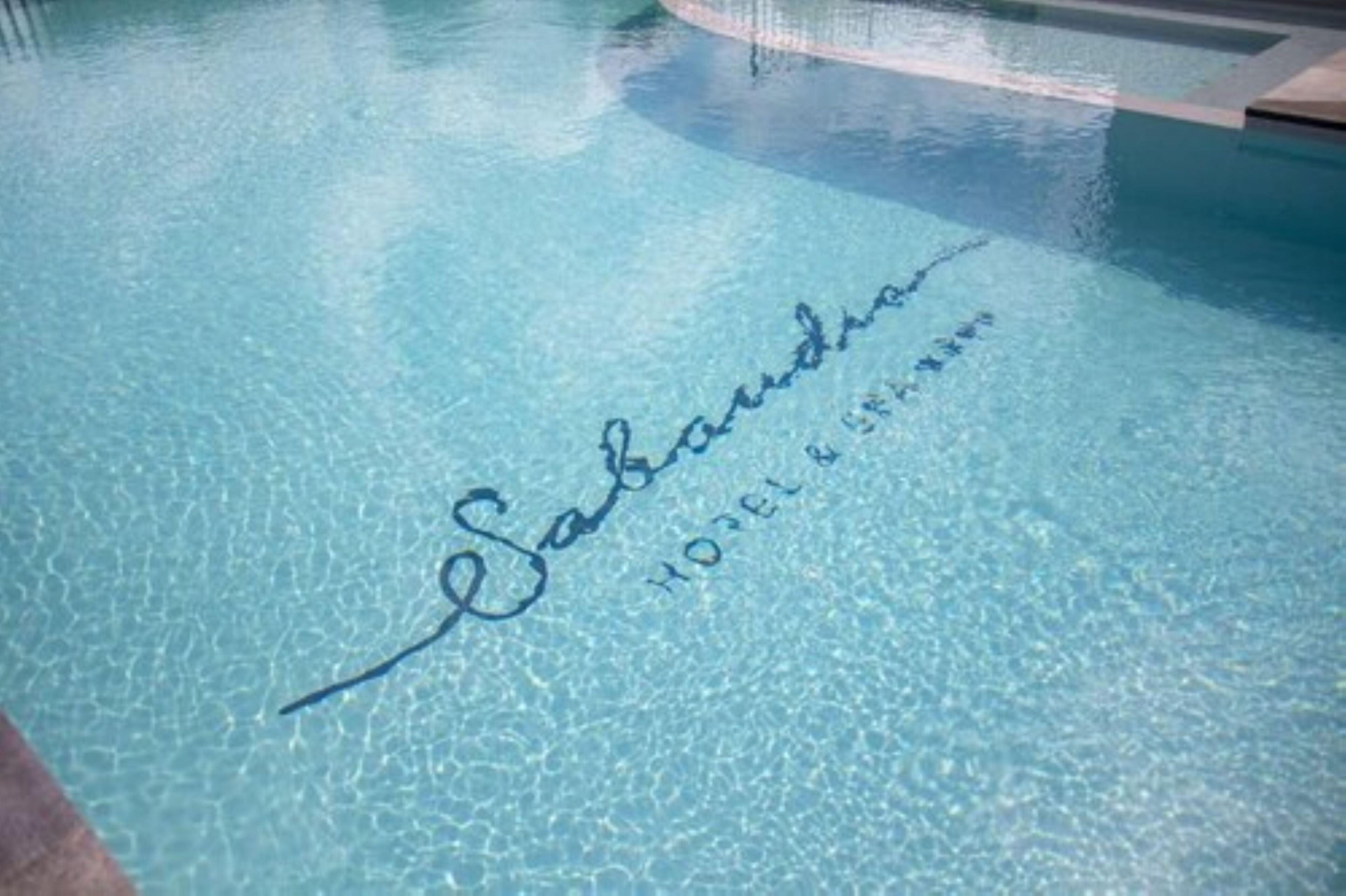 Une piscine dont la surface de l’eau porte une signature.