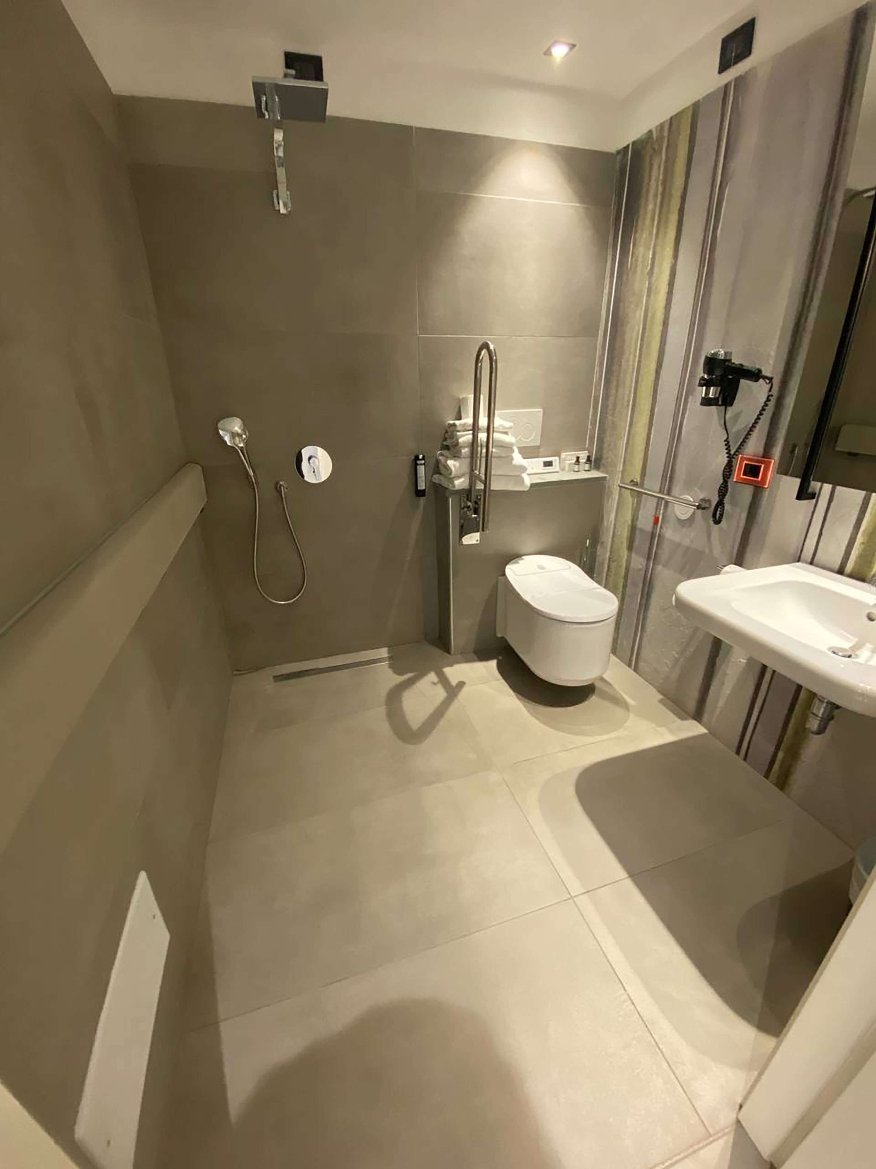 A modern bathroom with a shower, toilet, and sink.