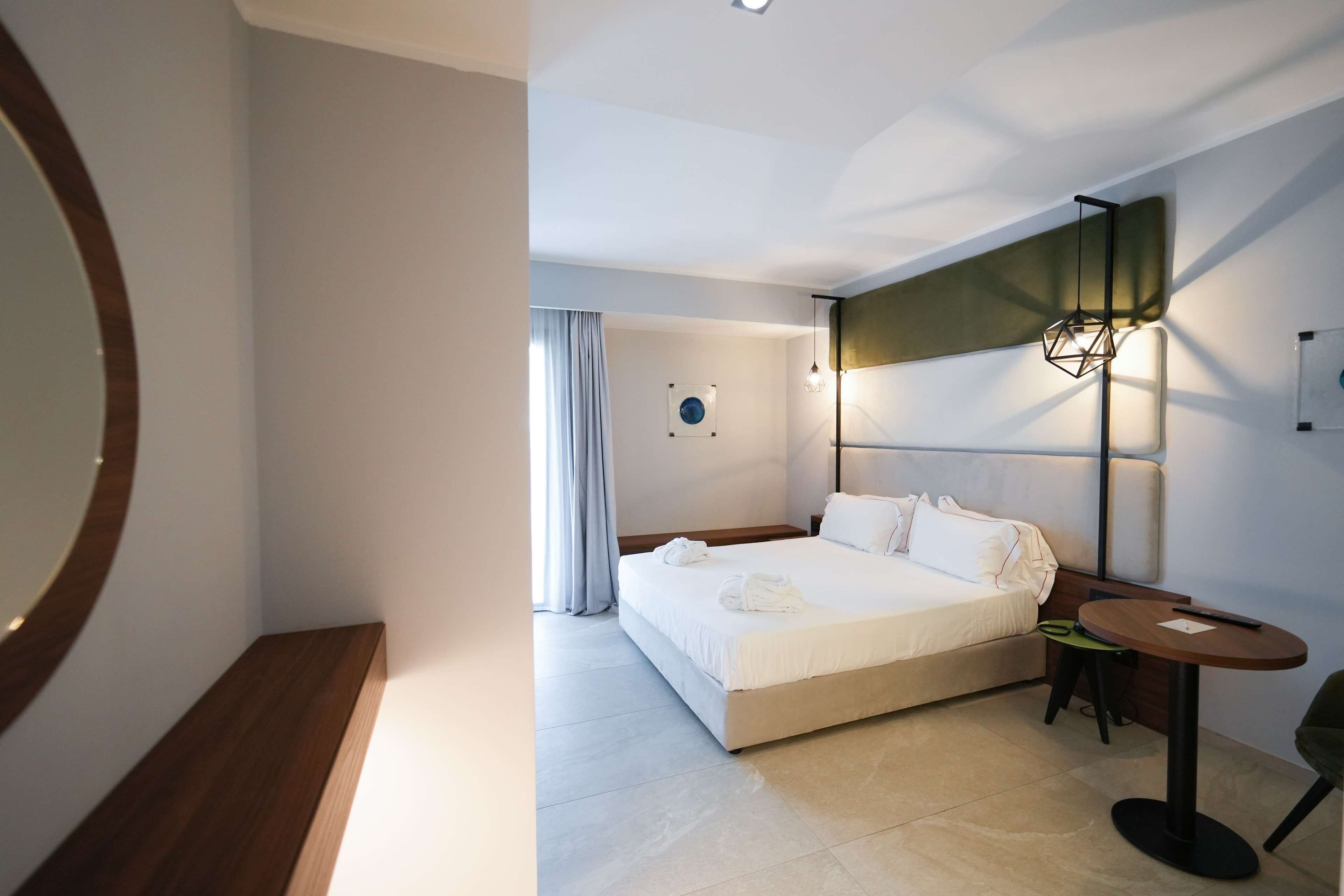 Una camera d'albergo moderna con un grande letto, un comodino, una sedia e una lampada da terra.
