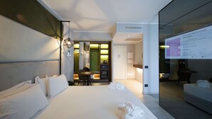 Une chambre d’hôtel moderne dotée d’un grand lit, d’un coin salon et d’un mur en verre.