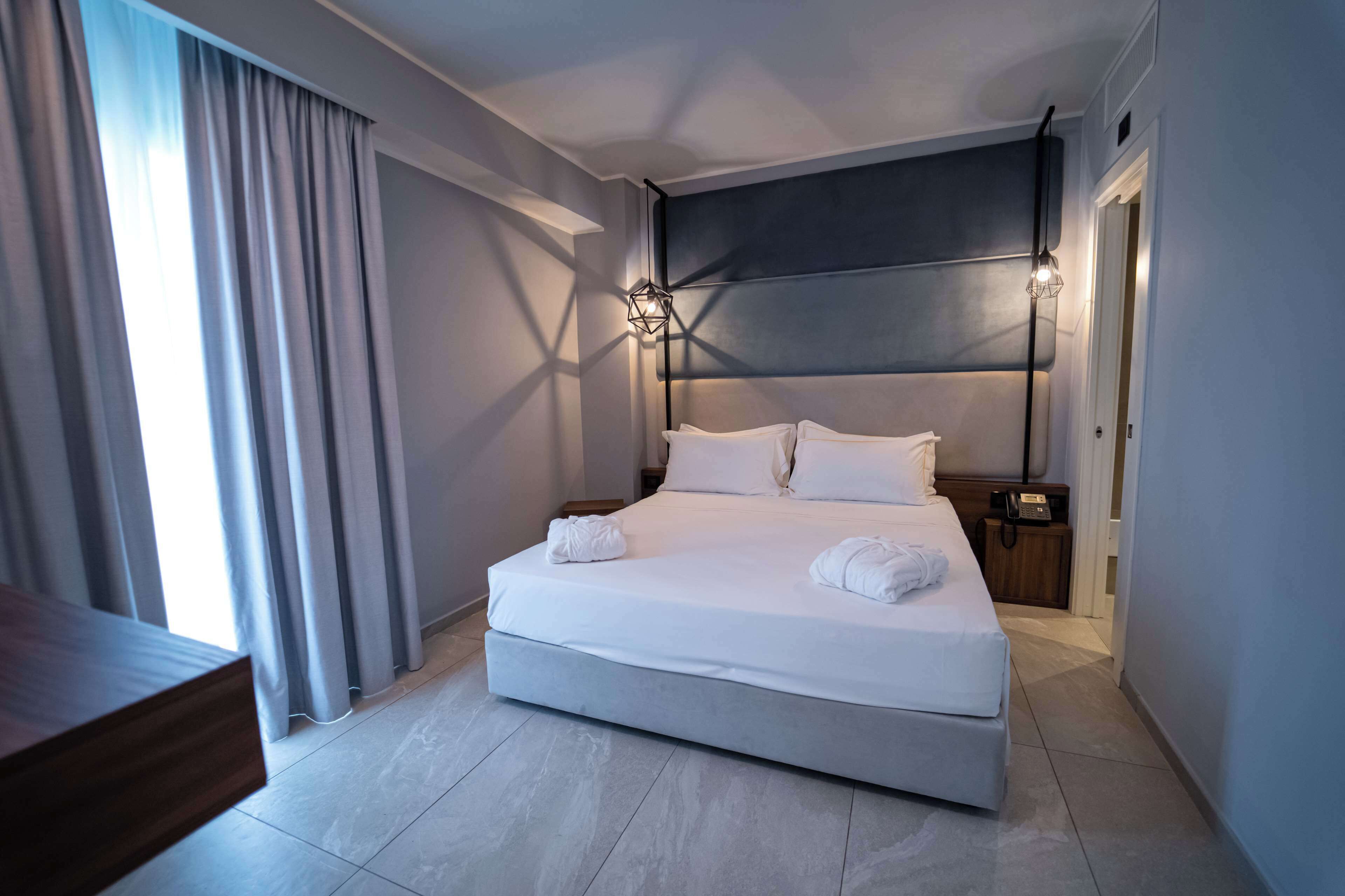 Ein modernes Hotelzimmer mit einem großen Bett, einem Nachttisch und einer Wandlampe.