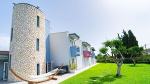 Un bâtiment moderne doté d’une tour en pierre, d’une structure à toit plat et d’une pelouse bien entretenue avec un hamac.