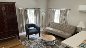 A living room with a sofa, armchair, and a small round table. - Sunny Coach House in Historic Oak Park (Oak Park)