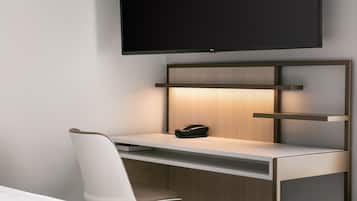 Una habitación de hotel moderna con un escritorio minimalista, un televisor de pantalla plana en la pared y una silla elegante.