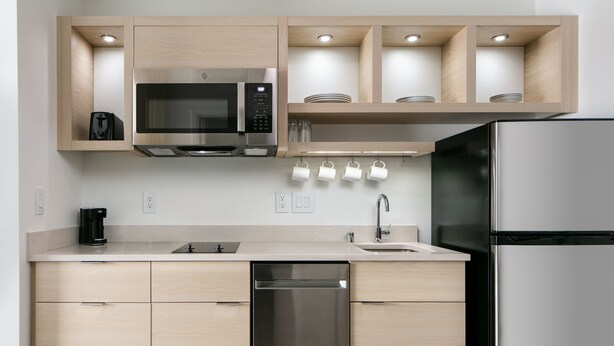 A modern kitchen with a built-in microwave, stainless steel refrigerator, and a dishwasher. - TownePlace Suites by Marriott Oconomowoc (Oconomowoc)