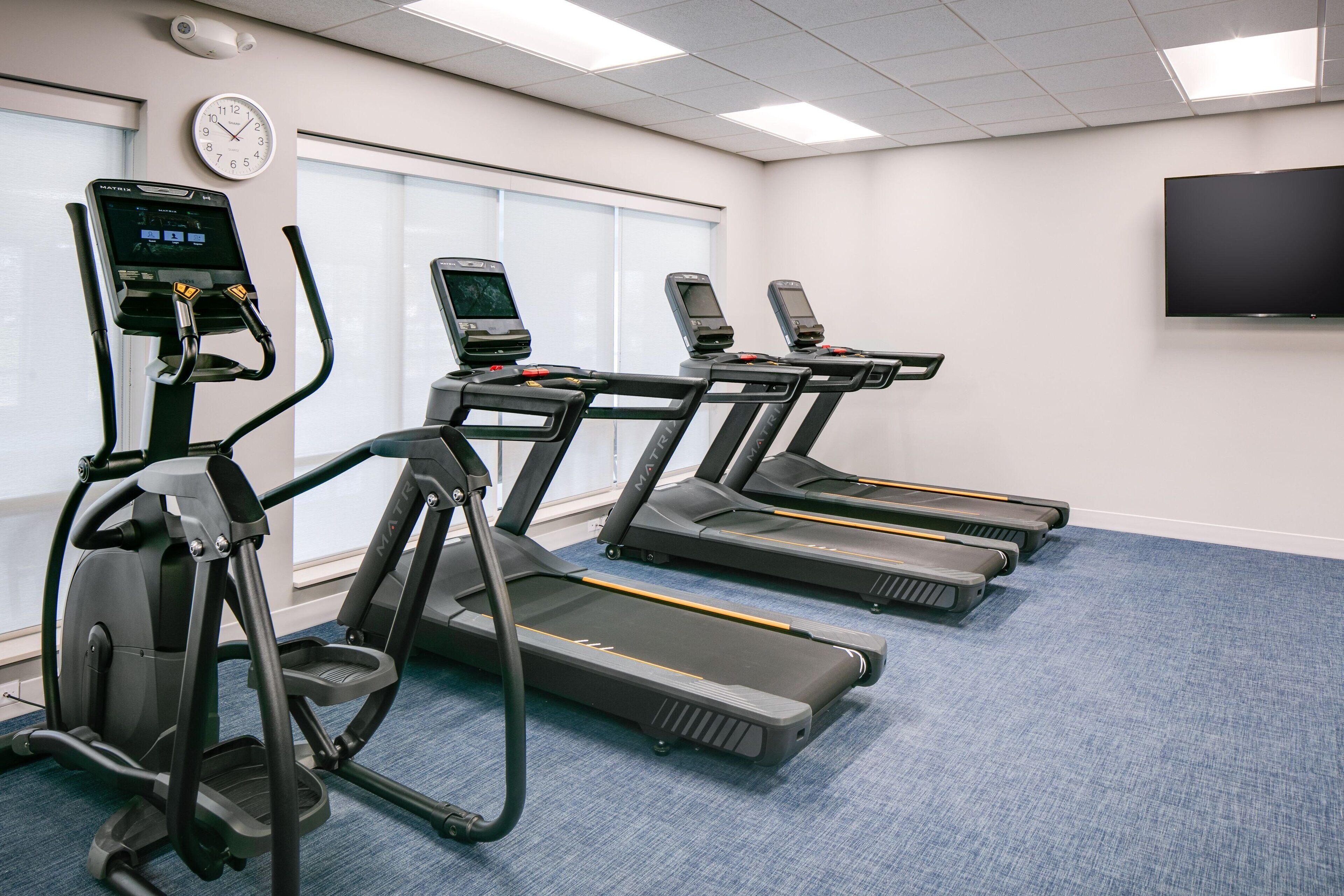 Une salle de remise en forme équipée de tapis de course, d’un vélo d’appartement et d’un rameur.