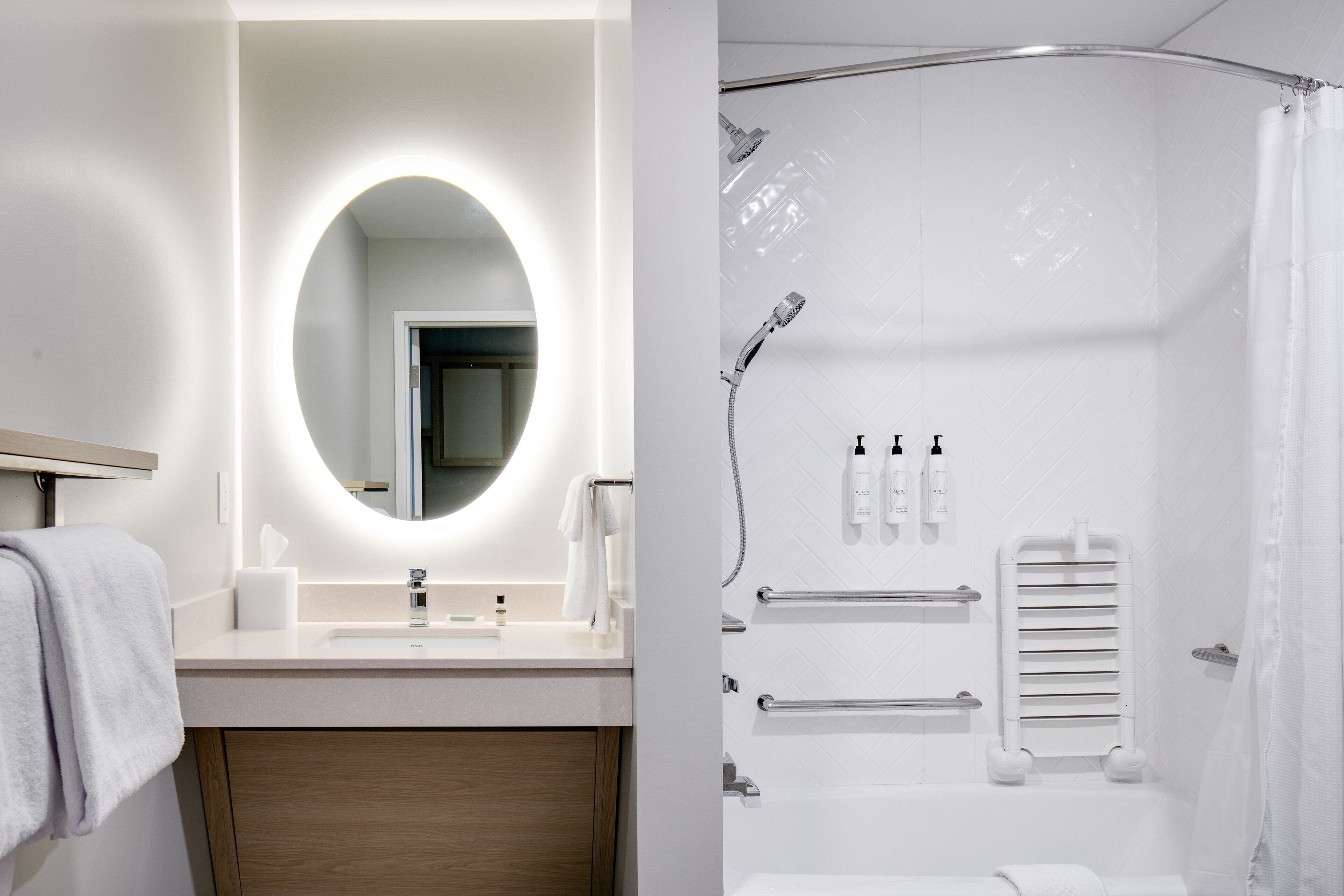 A modern bathroom with a round mirror, a sink, and a shower area.